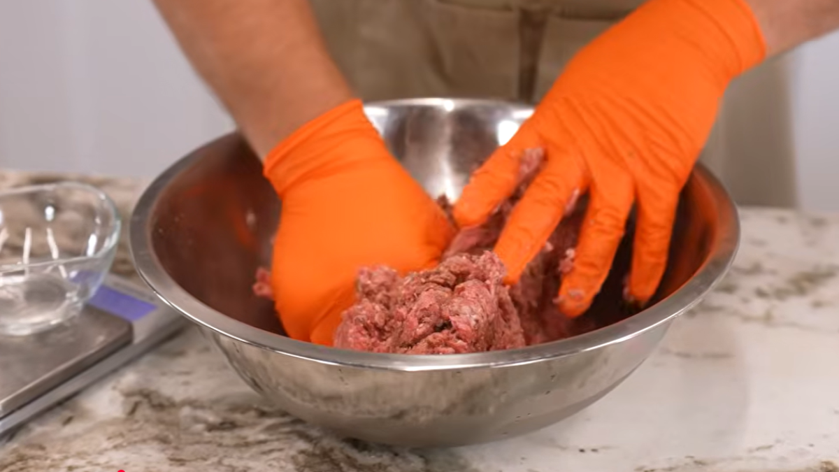 Meat in mixing bowl being mixed by hand